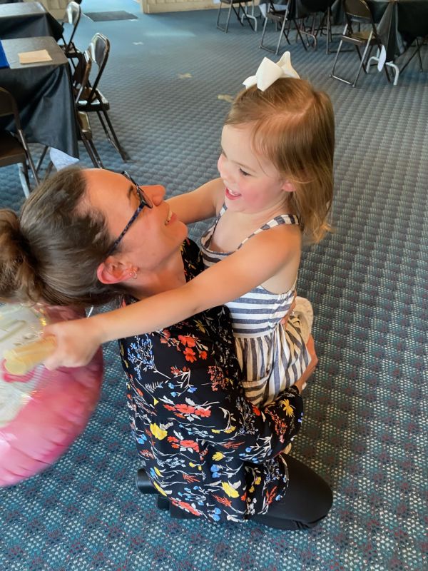 Stephanie getting big hugs from a friend's daughter